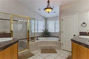 Primary bathroom with large shower w/bench, jacuzzi tub, tile floors, vaulted ceiling, dual vanities and private toilet