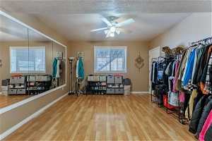 Dance studio/ work out room with spacious closet featuring light hardwood / wood-style flooring, natural light and ceiling fan