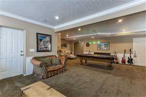 Game room featuring crown molding, a textured ceiling, dark carpet, and pool table