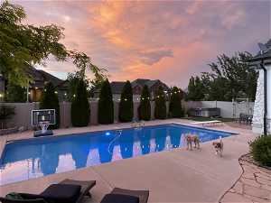 Pool at dusk with a diving board and 2 sitting areas