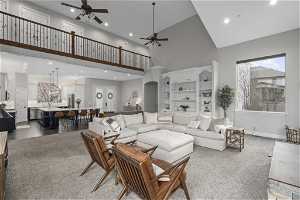 Living room featuring high vaulted ceiling, ceiling fan with notable chandelier, and hardwood / wood-style floors