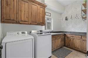 Laundry room featuring sink, light tile flooring, cabinets, and washing machine and dryer