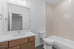 Full bathroom with vanity, tiled shower / bath combo, toilet, and tile patterned floors