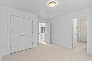 Unfurnished bedroom featuring ensuite bath, a closet, and light colored carpet