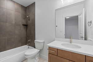 Full bathroom featuring vanity, tiled shower / bath, and toilet