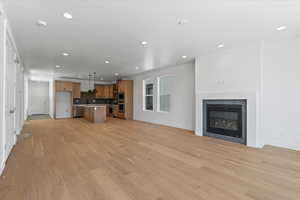 Unfurnished living room with sink, a fireplace, and light wood-type flooring