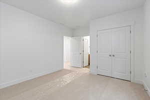 Unfurnished bedroom with a closet and light colored carpet