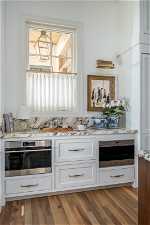 Kitchen featuring white cabinetry, a healthy amount of sunlight, stainless steel oven, and hardwood / wood-style flooring