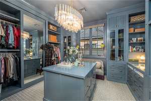 Spacious closet featuring an inviting chandelier and light carpet