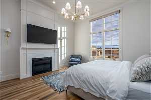 Bedroom featuring a tile fireplace, multiple windows, an inviting chandelier, and hardwood / wood-style flooring