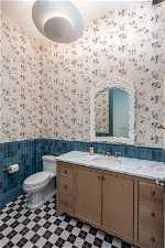 Bathroom featuring vanity, tile walls, toilet, backsplash, and tile flooring