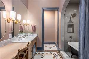 Bathroom with a notable chandelier, vanity, a bath, and tile flooring