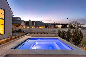 Pool at dusk featuring a pergola, an in ground hot tub, and a patio