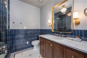 Bathroom with tasteful backsplash, toilet, vanity, and tile walls