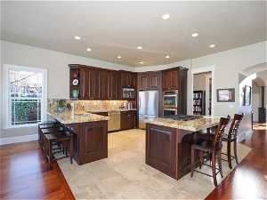 Chef's kitchen in great room with rich cabinetry, granite counters, gas stove, stone floors and two bars