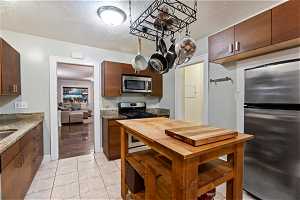 Kitchen with stainless steel appliances, light stone countertops, and light tile floors
