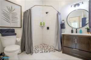 Bathroom with large vanity, toilet, tile flooring, and curtained shower
