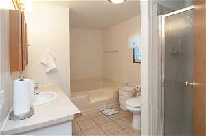 Full bathroom featuring vanity, toilet, tile flooring, and independent shower and bath