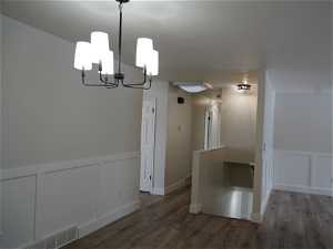 Empty room with dark wood-type flooring and a notable chandelier