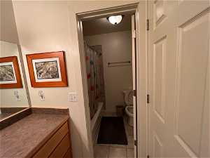 Full bathroom with tile floors, shower / tub combo with curtain, toilet, and vanity
