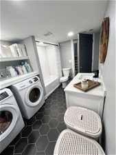 Laundry area with independent washer and dryer, dark tile flooring, and sink