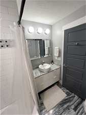 Bathroom with shower / tub combo, vanity, and a textured ceiling