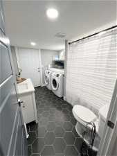 Laundry room with dark tile flooring, sink, and washer and dryer
