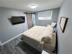 Bedroom with a barn door and dark wood-type flooring