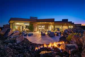 Back house at dusk with an outdoor living space with a fire pit and a patio area