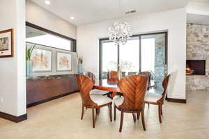 Tiled dining area featuring a notable chandelier and a fireplace