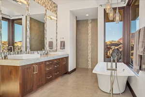 Bathroom with a bath to relax in, double sink vanity, and tile flooring