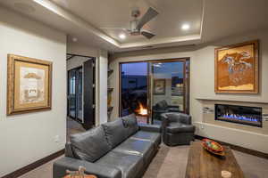 Carpeted living room featuring a tray ceiling and ceiling fan