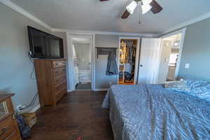 Bedroom with crown molding, dark hardwood / wood-style flooring, a closet, ensuite bathroom, and ceiling fan