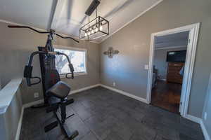 Dining area featuring crown molding, dark tile flooring, and vaulted ceiling