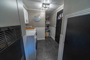 Laundry room with crown molding, cabinets, dark tile floors, and washing machine and dryer