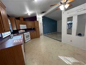 Kitchen featuring ceiling fan, light tile floors, white appliances, sink, and a textured ceiling