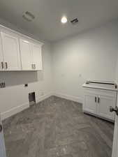 Washroom featuring visible vents, hookup for an electric dryer, gas dryer hookup, baseboards, and cabinet space