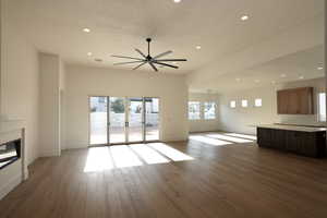 Unfurnished living room with a ceiling fan, a glass covered fireplace, recessed lighting, and wood finished floors