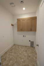 Laundry area with electric dryer hookup, hookup for a washing machine, cabinet space, and recessed lighting