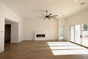 Unfurnished living room featuring recessed lighting, a ceiling fan, light wood-style flooring, and a glass covered fireplace
