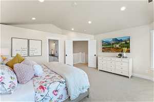 Carpeted bedroom with ensuite bathroom and lofted ceiling
