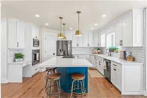 Kitchen with a kitchen island, white cabinetry, appliances with stainless steel finishes, and backsplash