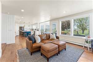 Living room with a baseboard heating unit, light hardwood / wood-style floors, and a wealth of natural light