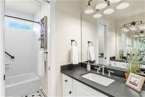 Bathroom with baseboard heating, vanity, tiled shower / bath, and an inviting chandelier