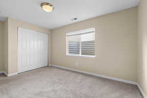 Unfurnished bedroom featuring a closet and light carpet