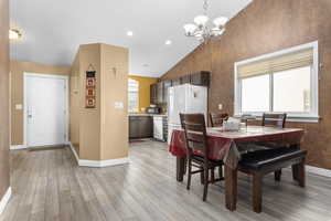 Dining room with an inviting chandelier, lofted ceiling, and light hardwood / wood-style floors