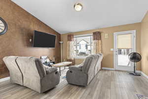 Living room with light wood-type flooring and vaulted ceiling