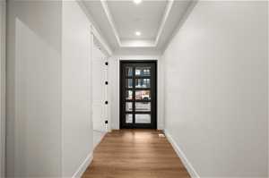 Doorway to outside featuring light hardwood / wood-style floors and a tray ceiling