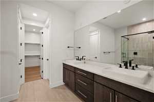 Bathroom with a shower with shower door, dual bowl vanity, and tile flooring
