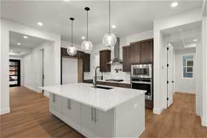 Kitchen featuring light hardwood / wood-style floors, appliances with stainless steel finishes, an island with sink, and backsplash